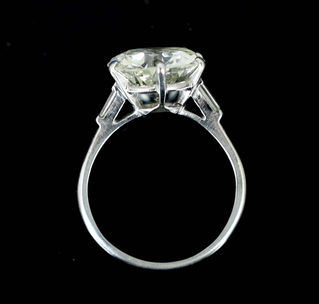 A platinum and single stone diamond set ring, with baguette cut diamond set shoulders